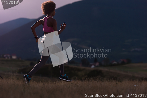 Image of Young African american woman jogging in nature