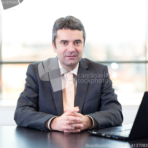 Image of Portrait of senior businessman in office with laptop computer.