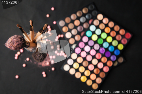 Image of Palette of eyeshadows with brushes isolated on black background