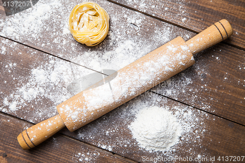 Image of Wooden rolling pin with flour and pasta