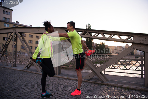 Image of jogging couple warming up and stretching in the city