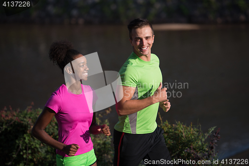 Image of young smiling multiethnic couple jogging in the city