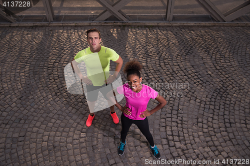 Image of portrait of a young multiethnic couple jogging in the city