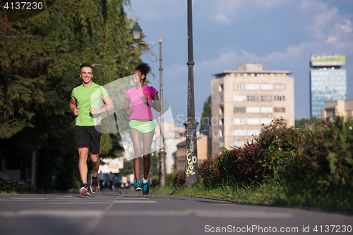 Image of young smiling multiethnic couple jogging in the city