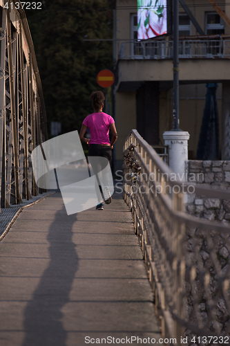 Image of african american woman running across the bridge