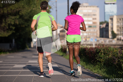 Image of young smiling multiethnic couple jogging in the city