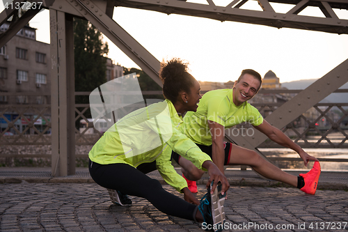 Image of jogging couple warming up and stretching in the city