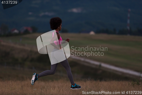 Image of Young African american woman jogging in nature