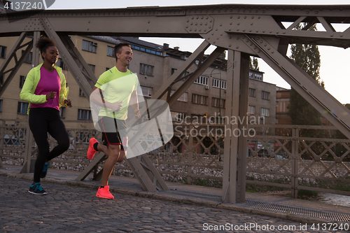 Image of young multiethnic couple jogging in the city