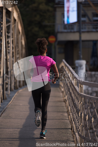 Image of african american woman running across the bridge