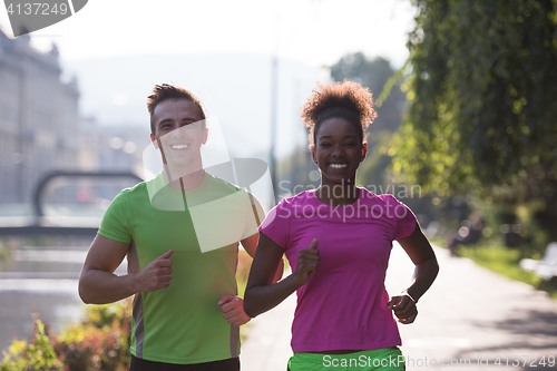 Image of young multiethnic couple jogging in the city