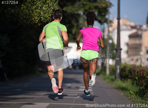 Image of young smiling multiethnic couple jogging in the city