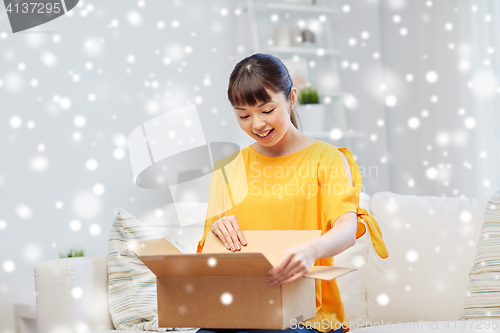 Image of happy asian young woman with parcel box at home