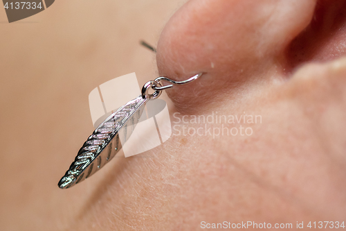 Image of Women\'s earring, metal feather, selective focus on the earring