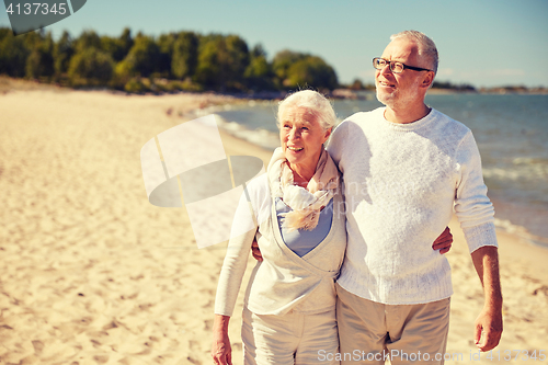 Image of happy senior couple walking along summer beach