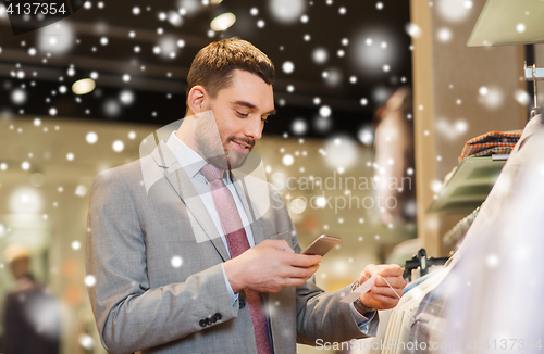 Image of man in suit with smartphone at clothing store
