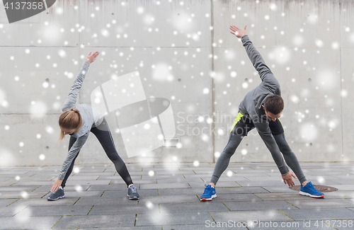 Image of couple of sportsmen stretching on city street