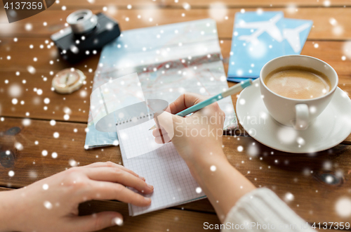 Image of close up of traveler hands with notepad and pencil