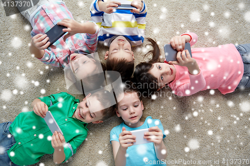 Image of happy children with smartphones lying on floor