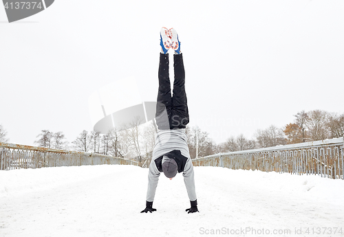 Image of young man doing handstand in winter