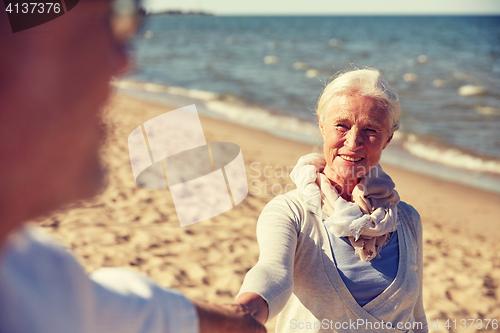 Image of happy senior couple holding hands summer beach