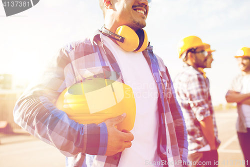 Image of close up of builder holding hardhat at building