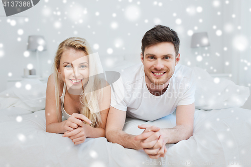 Image of happy couple lying in bed at home