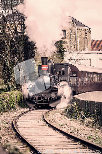 Image of Steamy veteran train driving on a railway