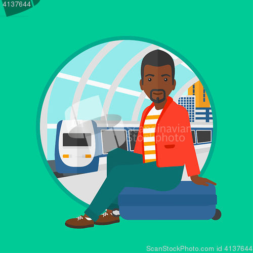 Image of Man sitting on suitcase at the train station.