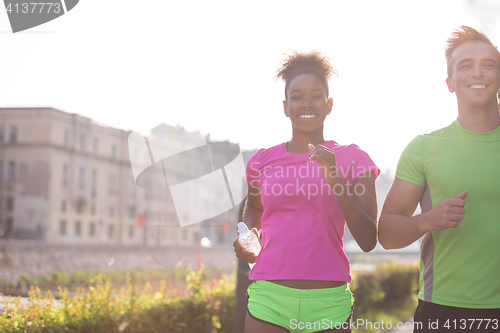 Image of young multiethnic couple jogging in the city