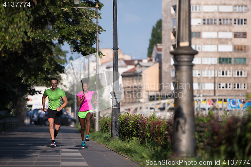 Image of young smiling multiethnic couple jogging in the city