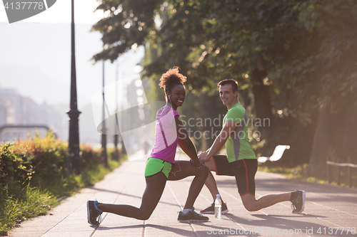 Image of jogging couple warming up and stretching in the city