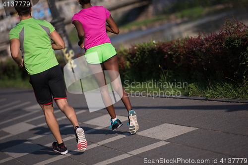 Image of young smiling multiethnic couple jogging in the city