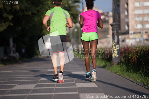 Image of young smiling multiethnic couple jogging in the city