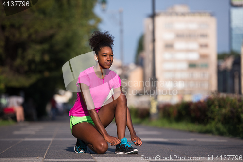 Image of African american woman runner tightening shoe lace