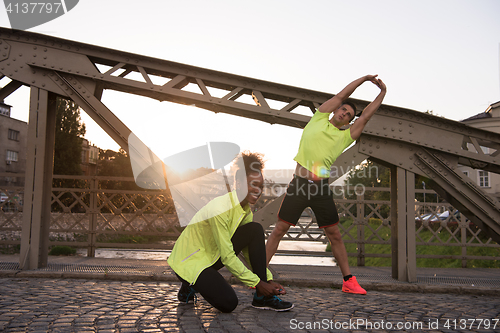 Image of jogging couple warming up and stretching in the city