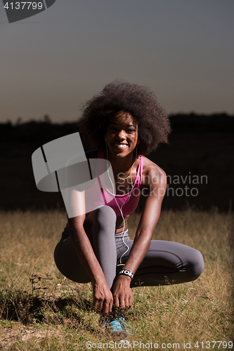 Image of black woman runner tightening shoe lace