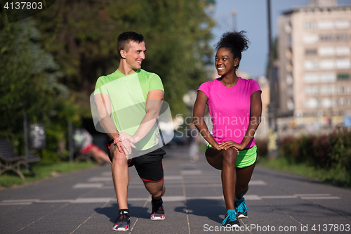 Image of jogging couple warming up and stretching in the city