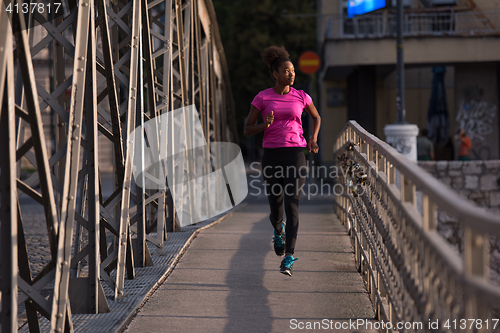 Image of african american woman running across the bridge