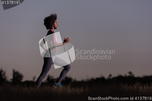 Image of Young African american woman jogging in nature