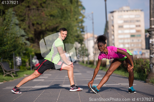 Image of jogging couple warming up and stretching in the city