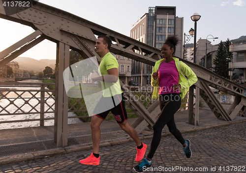 Image of young multiethnic couple jogging in the city
