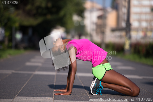 Image of sporty young african american woman stretching outdoors