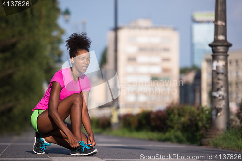 Image of African american woman runner tightening shoe lace