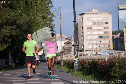 Image of young smiling multiethnic couple jogging in the city