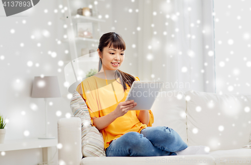 Image of happy young asian woman with tablet pc at home