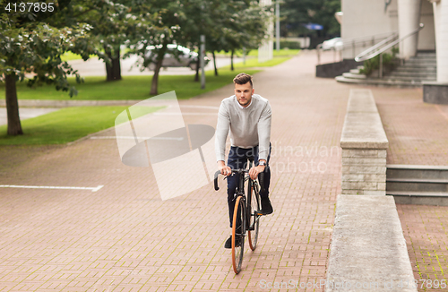 Image of young man riding bicycle on city street