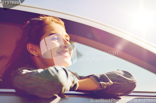 Image of happy teenage girl or young woman in car