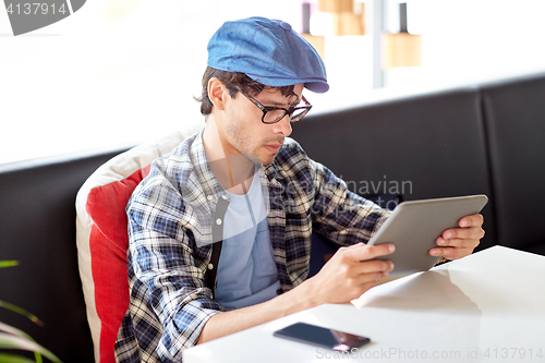 Image of man with tablet pc sitting at cafe table