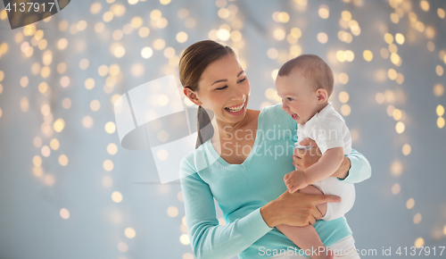 Image of happy young mother with little baby over lights